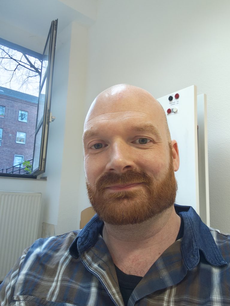 Benjamin Lang sitzt nach einem Fortbildungswochenende nachdenklich in einem Seminarraum und reflektiert die Aktive Imagination Fortbildung für seine Coaching-Arbeit